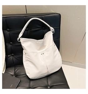 Détail du grand sac cabas blanc avec boucles argentées sur un fauteuil en cuir