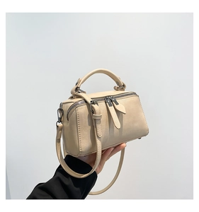 Close-up of beige boston bag featuring silver hardware and adjustable shoulder strap