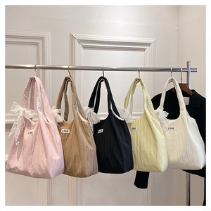 Detail view of colorful pleated tote bags with LOVE patches and delicate lace bow charms