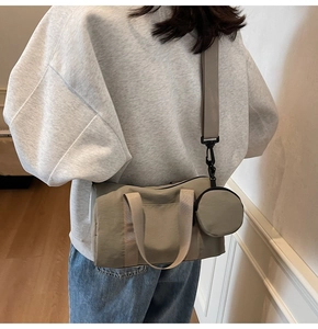 Vue détaillée du sac polochon en toile kaki avec large bandoulière et petite pochette
