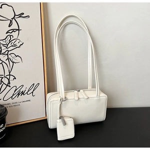 Dettaglio borsa a spalla minimalista in pelle bianca con piccolo ciondolo portamonete