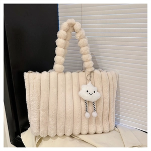 Close-up of cream faux fur tote bag featuring vertical stripes and pom-pom handle