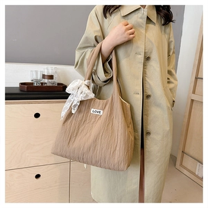 Detail of light khaki tote bag with pleated texture and a decorative white lace bow