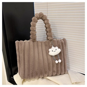 Detail of camel plush tote bag with vertical stripes, pom-pom handle and cloud charm