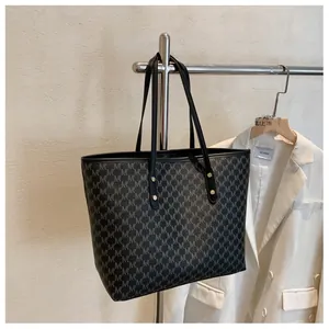 Dettaglio della borsa tote grande con elegante motivo a monogramma M su pelle nera