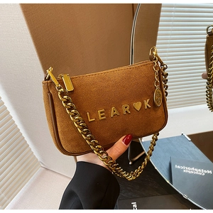 Detail of caramel suede bag featuring gold chain strap and metallic brand logo accents