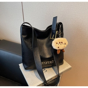 Detail of black pebbled leather tote with golden summer lettering and plush charm