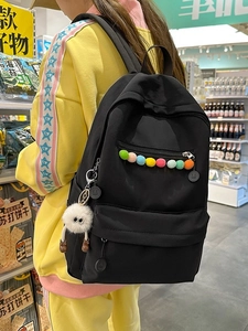 Black minimalist backpack with colorful pom-poms and cute monster pendant on straps