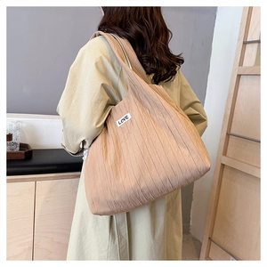 Detail shot of khaki tote bag texture and Love label on shoulder while being worn