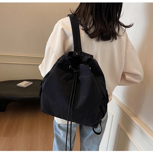 Vue arrière d'une femme portant un sac à dos noir à cordon en nylon dans un décor moderne