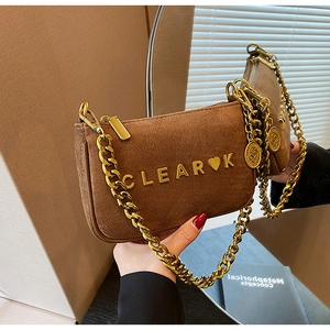 Detail of a brown suede handbag featuring a chunky gold chain and metal logo lettering
