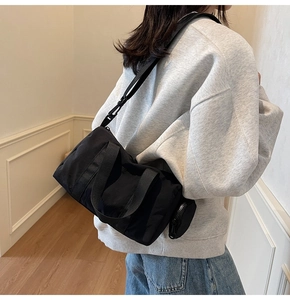 Gros plan du sac Boston en nylon noir porté en bandoulière avec un petit porte-monnaie