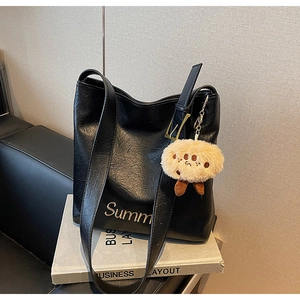 Detail of black leather tote bag with Summer embroidery and cute plush pendant