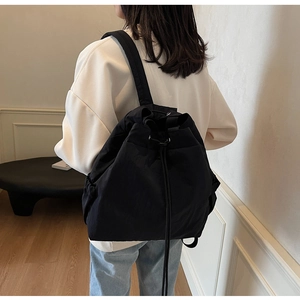 Vue arrière d'un sac à dos noir à cordon minimaliste porté par un mannequin en intérieur