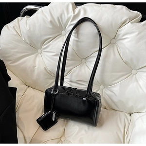 Dettaglio di una borsa a spalla in pelle verniciata nera lucida con mini pochette
