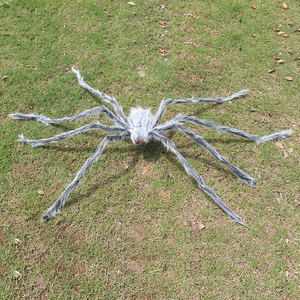 Close-up of giant Halloween spider with grey plush fur and red eyes on grass