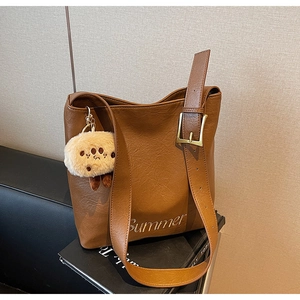 Detail of caramel faux leather bag with Summer embroidery and cute teddy bear charm