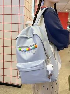 Pastel blue student backpack with colorful pom-poms and cute plush charm in use