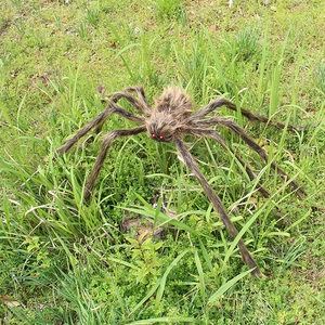 Giant Halloween plush spider with glowing red eyes and furry legs on green grass