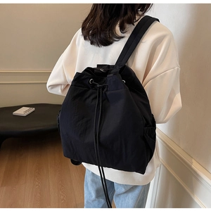 Vue latérale d'un sac à dos noir à cordon porté par un mannequin dans un salon chic