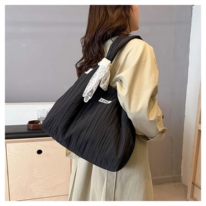 Detail of black pleated tote bag featuring white lace bow and LOVE text label detail