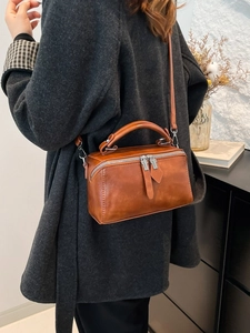 Caramel brown square shoulder bag with top handle and metallic strap displayed by model