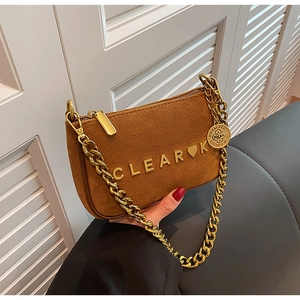 Close-up of brown faux suede handbag with gold chain strap and metal letter logo