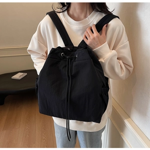 Détail du sac à dos noir à cordon montrant la texture nylon et les œillets en argent