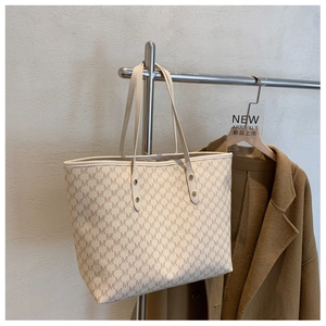 Dettaglio della borsa shopper beige con stampa monogramma M e doppi manici sottili
