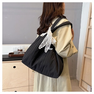 Detail of black pleated tote bag with white lace bow and smooth nylon texture
