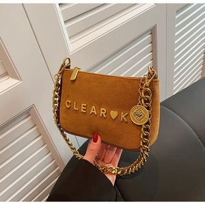 Detail of a brown faux suede bag featuring a gold chain strap and metal letters