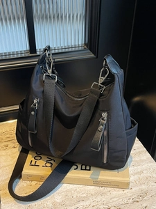 Minimalistische schwarze Nylon-Schultertasche mit silbernen Reißverschlüssen auf Marmor