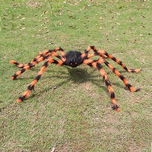 Araña gigante de Halloween con patas rayadas naranja y negro sobre el césped
