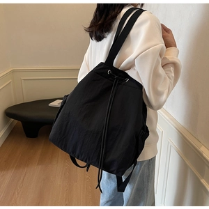 Vue détaillée d'un sac à dos léger en nylon noir avec cordon sur le dos d'un modèle