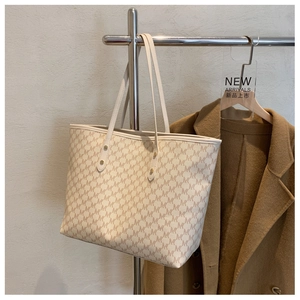 Dettaglio della borsa tote beige con monogramma M marrone e manici in pelle rinforzata