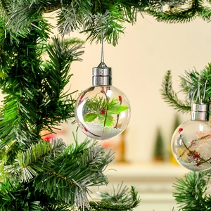 Primo piano di una palla di Natale trasparente con bacche e neve su un albero