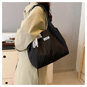 Detail of black pleated tote bag featuring lace bow decoration and Love brand patch