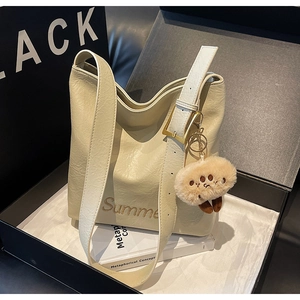 Detail of cream white leather tote featuring Summer embroidery and a plush cat paw charm