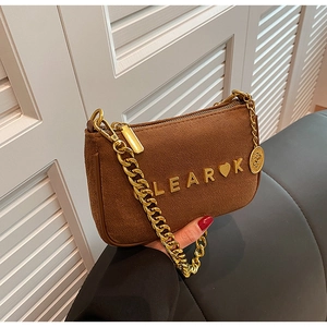 Detail of brown suede crossbody bag with gold chain strap and metallic heart logo