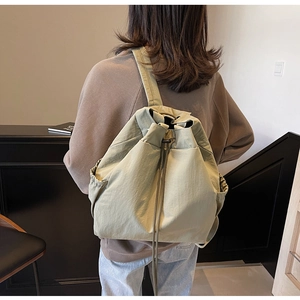 Gros plan du sac à dos en nylon vert pois avec cordon porté par un mannequin en studio