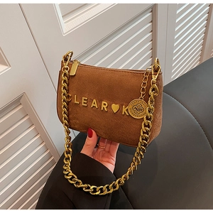 Detail of dark brown matte suede bag featuring gold letter logo and bold chain strap
