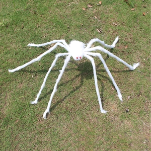 Detailed view of large white fuzzy spider prop with red eyes on a green lawn for Halloween
