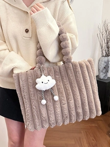 Brown plush tote bag with furry ball handle and cloud charm in a cozy indoor setting