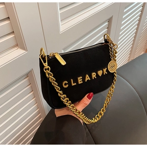 Detail of black suede shoulder bag featuring gold CLEAR K hardware and metal chain strap