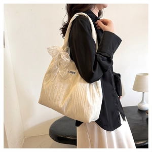 White quilted tote bag with lace bow and LOVE patch shown on a shoulder for daily styling