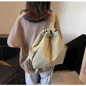 Vue détaillée d'un sac à dos à cordon vert olive clair avec poches latérales sur modèle