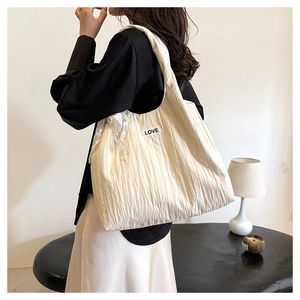 Detail of white pleated tote bag featuring lace ribbon bow and LOVE label on side