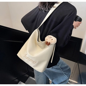 Detail of cream tote bag with Summer embroidery and plush bear charm on strap