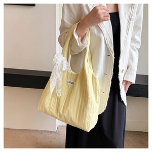 Detail of yellow quilted tote bag with lace bow pendant and LOVE label side view