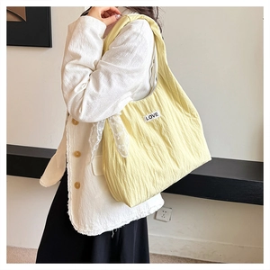 Detail of yellow pleated tote bag featuring LOVE patch and lace scarf on casual shoulder strap